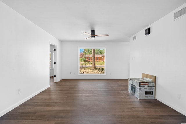 unfurnished room featuring dark wood-style floors, visible vents, ceiling fan, and baseboards