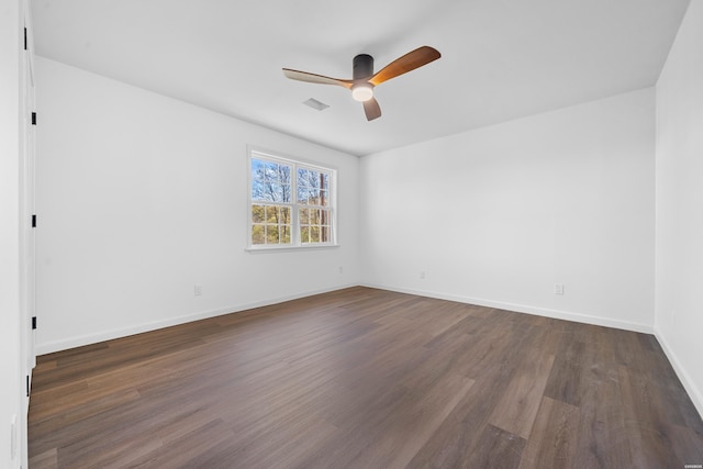 spare room with dark wood-type flooring, visible vents, baseboards, and a ceiling fan