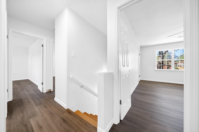 corridor featuring dark wood-style flooring, baseboards, and an upstairs landing