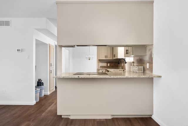 kitchen featuring dark wood-style flooring, a sink, visible vents, and light stone countertops