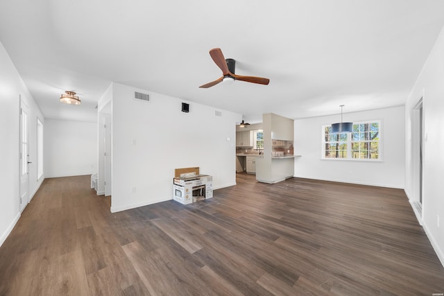 unfurnished living room with a ceiling fan, baseboards, visible vents, and dark wood-type flooring