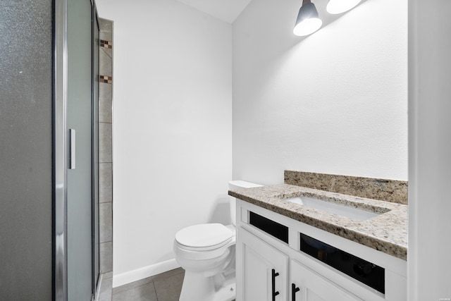 bathroom featuring a shower with shower door, vanity, toilet, and tile patterned floors