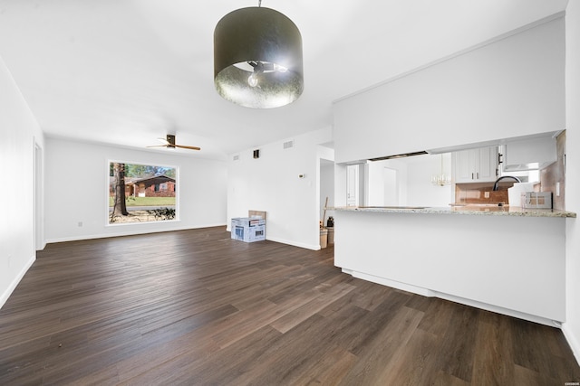 unfurnished living room featuring visible vents, dark wood-style flooring, a ceiling fan, and baseboards