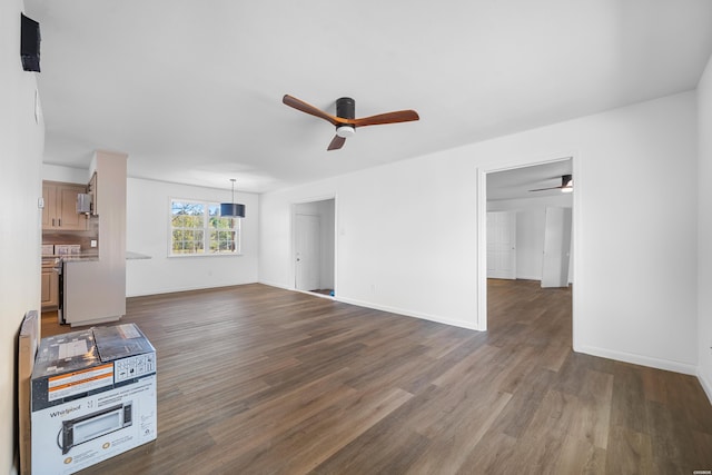 unfurnished living room featuring dark wood-style floors, baseboards, and a ceiling fan