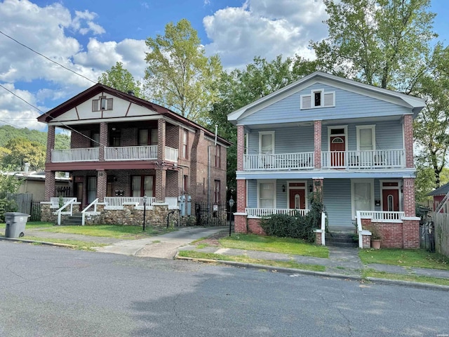 view of front of home featuring a porch, brick siding, fence, and a balcony