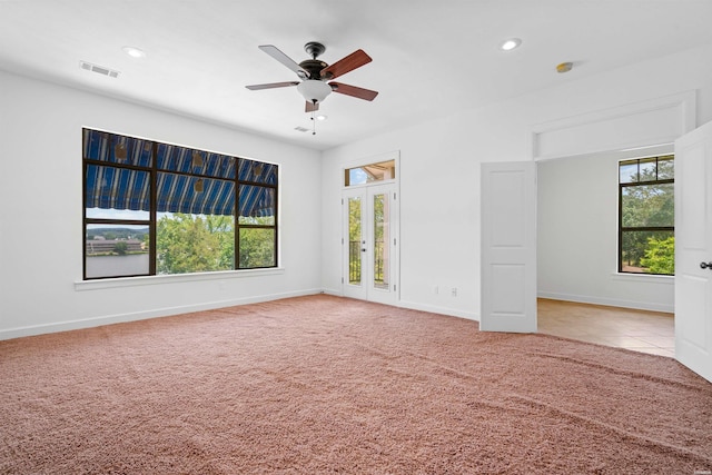 unfurnished room with baseboards, a healthy amount of sunlight, visible vents, and light colored carpet