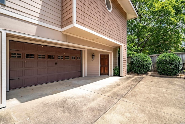 garage featuring driveway and fence