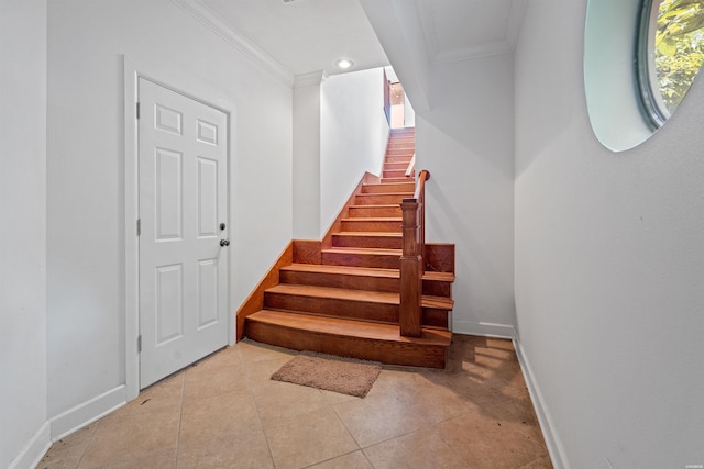 staircase with crown molding, baseboards, and tile patterned floors