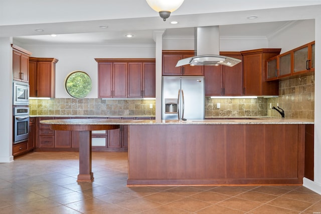 kitchen with light stone counters, island range hood, ornamental molding, appliances with stainless steel finishes, and glass insert cabinets