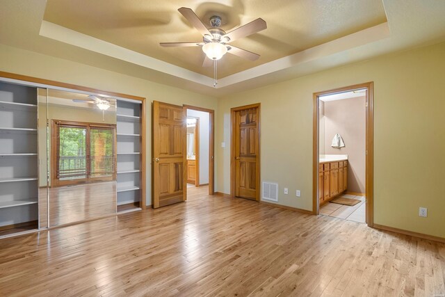 111 Black Oak Ct, Hot Springs, AR 71913 - unfurnished bedroom with a raised ceiling, light wood-style flooring, ensuite bath, and ceiling fan