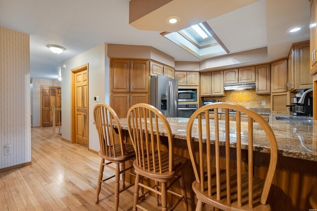111 Black Oak Ct, Hot Springs, AR 71913 - kitchen with stainless steel appliances, under cabinet range hood, a skylight, light wood finished floors, and tasteful backsplash