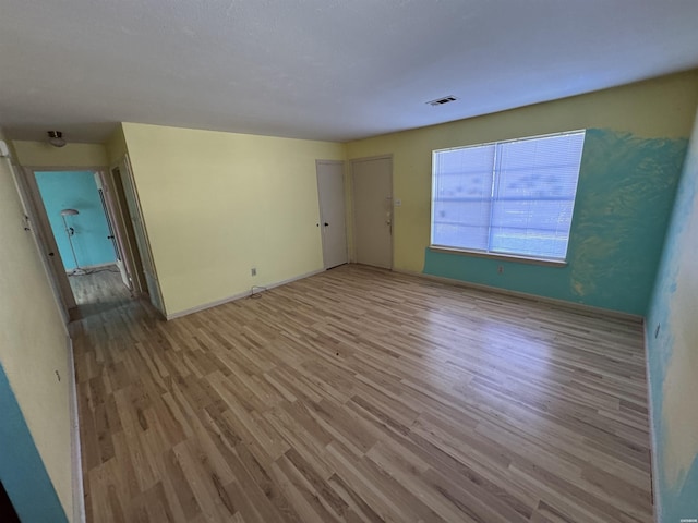 spare room featuring light wood-style floors, baseboards, and visible vents