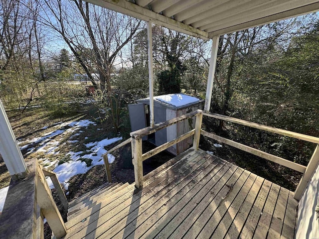 snow covered deck featuring a storage unit and an outdoor structure