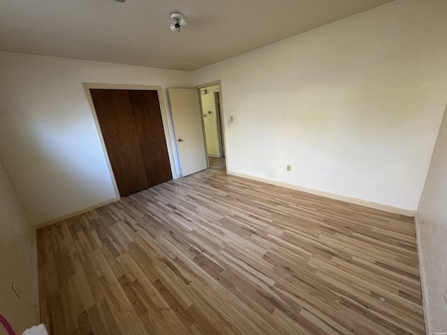 unfurnished bedroom featuring a closet, light wood-style flooring, and baseboards