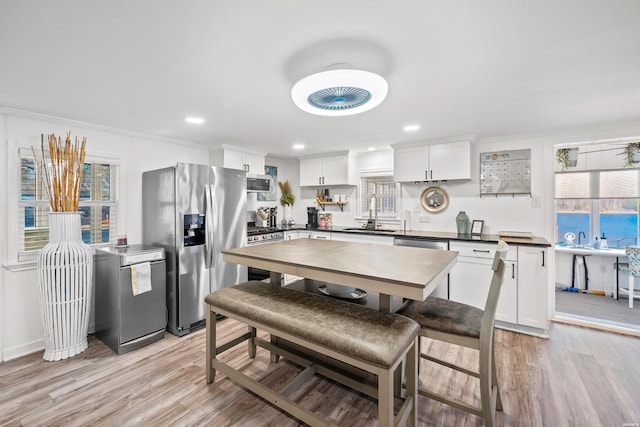 kitchen featuring light wood-type flooring, stainless steel appliances, dark countertops, and white cabinets