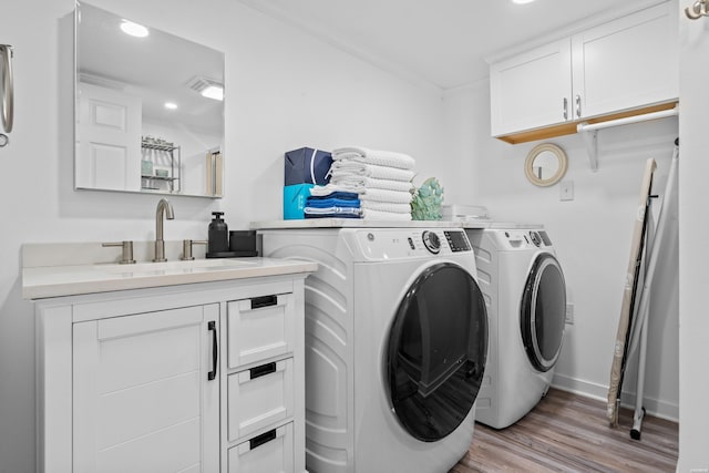 laundry room featuring light wood finished floors, baseboards, washer and dryer, cabinet space, and a sink