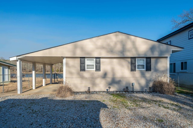 rear view of property with an attached carport and fence