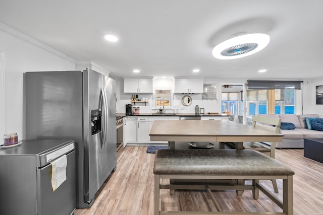 kitchen with dark countertops, light wood-type flooring, recessed lighting, stainless steel appliances, and white cabinetry