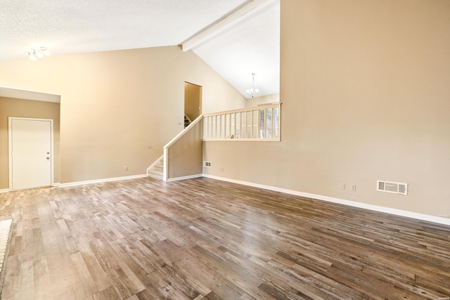 empty room featuring vaulted ceiling with beams, stairs, visible vents, and wood finished floors