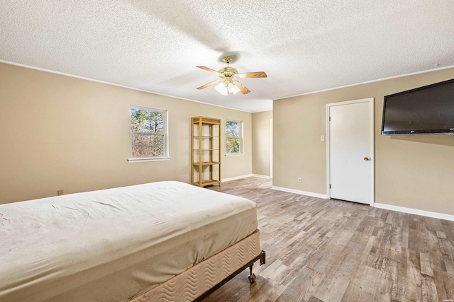 bedroom featuring a textured ceiling, ceiling fan, light wood-type flooring, and baseboards