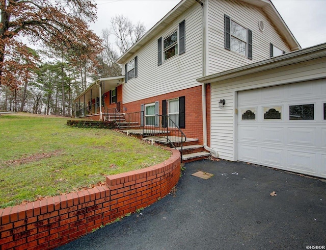 view of property exterior with a garage, brick siding, a lawn, and driveway