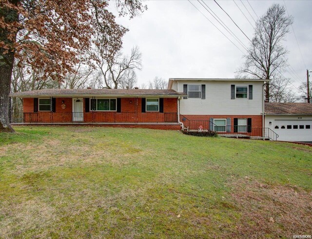 split level home with an attached garage, brick siding, and a front yard