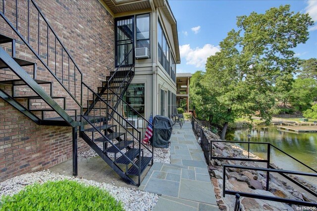 view of property exterior featuring a patio, brick siding, stairway, and a water view