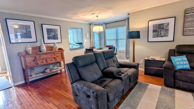 living area featuring a textured ceiling, baseboards, wood finished floors, and crown molding