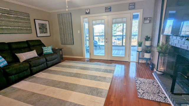 living room with french doors, a fireplace, ornamental molding, wood finished floors, and baseboards