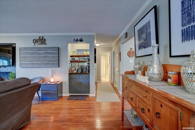 interior space featuring a textured ceiling, ornamental molding, light wood-type flooring, and a fireplace