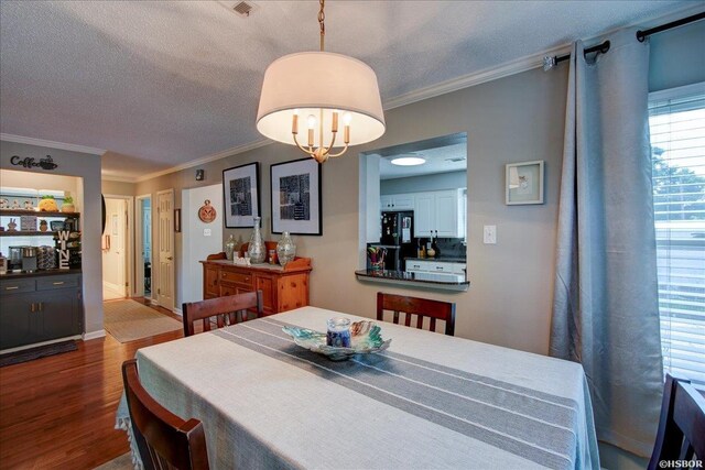 dining area featuring dark wood-style floors, a textured ceiling, a chandelier, and crown molding