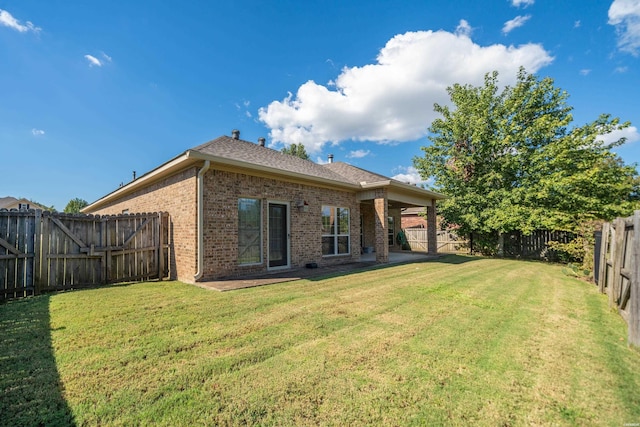 rear view of house featuring brick siding, a lawn, and a fenced backyard