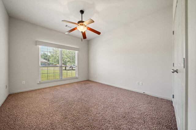 spare room with baseboards, carpet floors, visible vents, and a ceiling fan