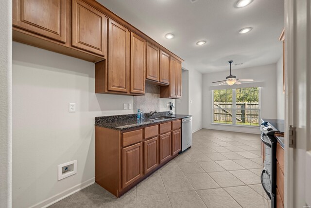 kitchen featuring light tile patterned floors, range with electric cooktop, brown cabinetry, dark stone countertops, and stainless steel dishwasher