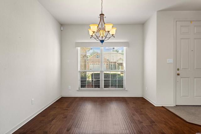 unfurnished dining area featuring baseboards, dark wood finished floors, and a notable chandelier