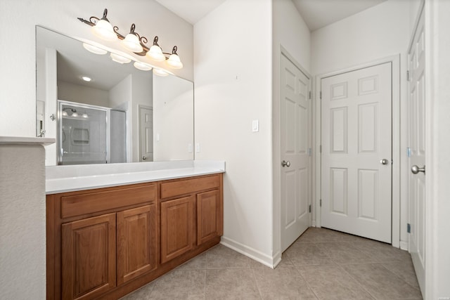 bathroom with a stall shower, vanity, baseboards, and tile patterned floors