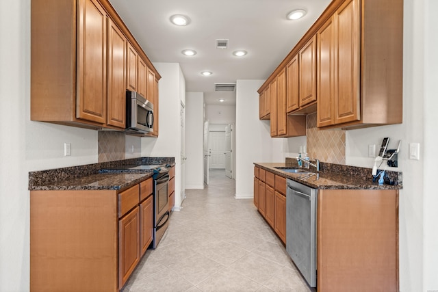 kitchen with brown cabinets, visible vents, appliances with stainless steel finishes, and dark stone counters