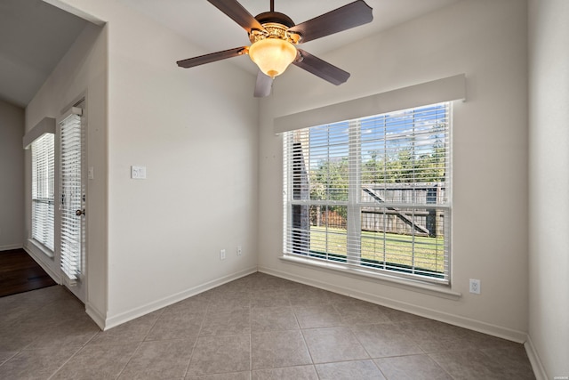 empty room with ceiling fan, light tile patterned flooring, and baseboards