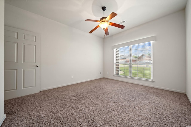 empty room with carpet floors, ceiling fan, visible vents, and baseboards