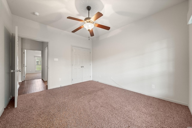 unfurnished bedroom featuring a closet, dark colored carpet, and a ceiling fan