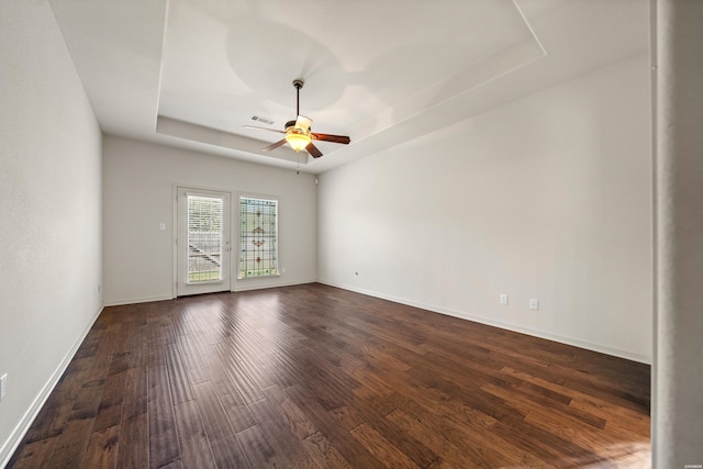 unfurnished room with dark wood finished floors, a raised ceiling, visible vents, ceiling fan, and baseboards