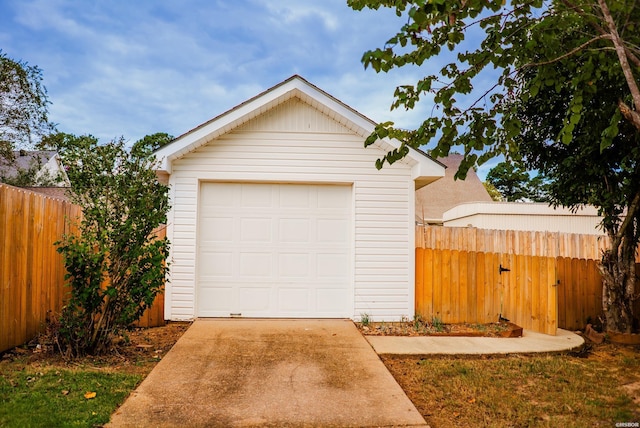 detached garage with concrete driveway and fence