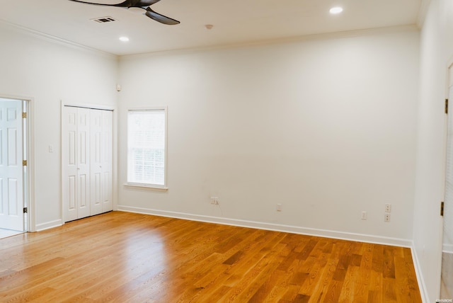 spare room featuring visible vents, ornamental molding, ceiling fan, wood finished floors, and baseboards