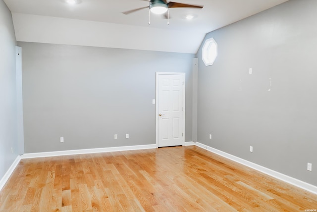 spare room with vaulted ceiling, light wood-type flooring, a ceiling fan, and baseboards