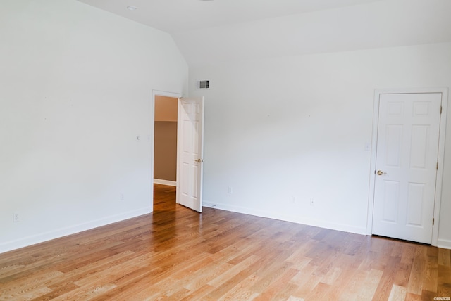 spare room featuring vaulted ceiling, baseboards, visible vents, and light wood-style floors