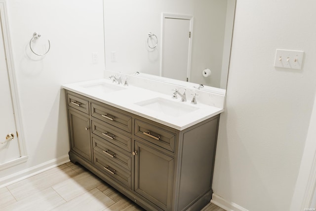 bathroom with double vanity, a sink, and baseboards