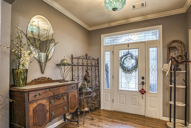 entryway featuring ornamental molding, visible vents, a textured ceiling, and wood finished floors