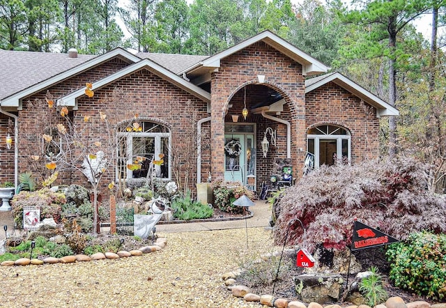 view of front of home featuring brick siding and roof with shingles