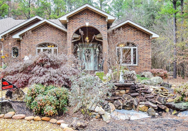 view of front of home with brick siding and roof with shingles