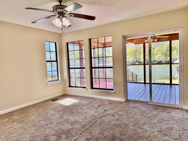 spare room featuring a water view, a healthy amount of sunlight, and carpet